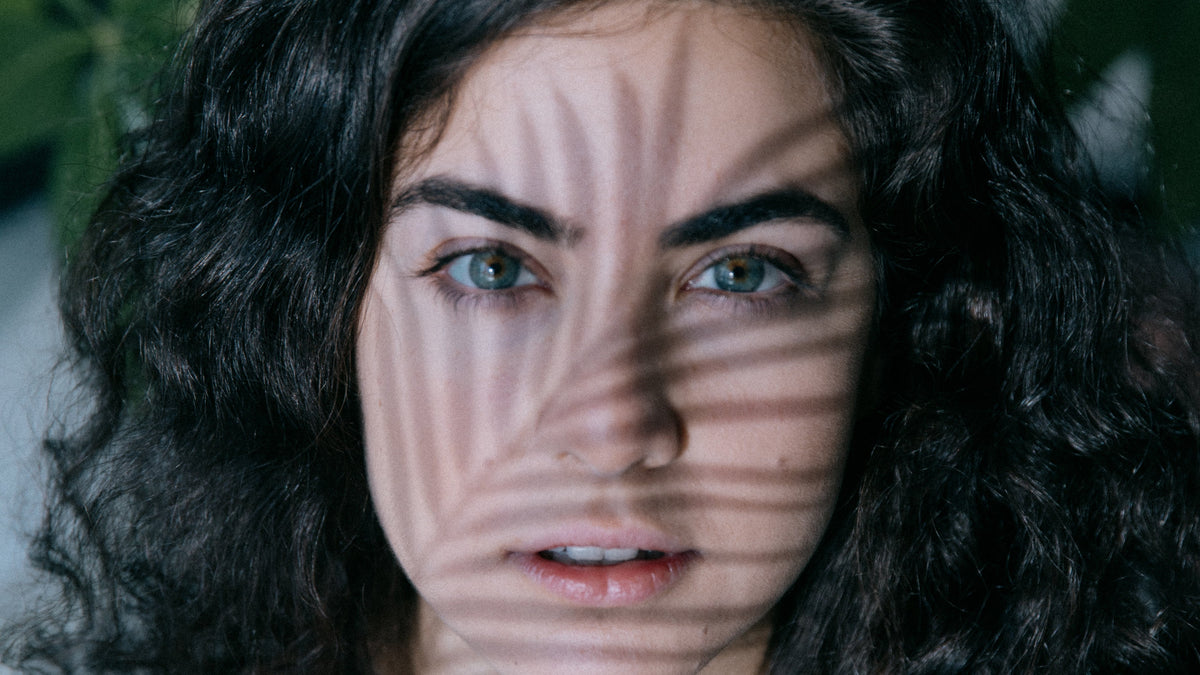 Person looks forward with the shadow of a leaf on their face